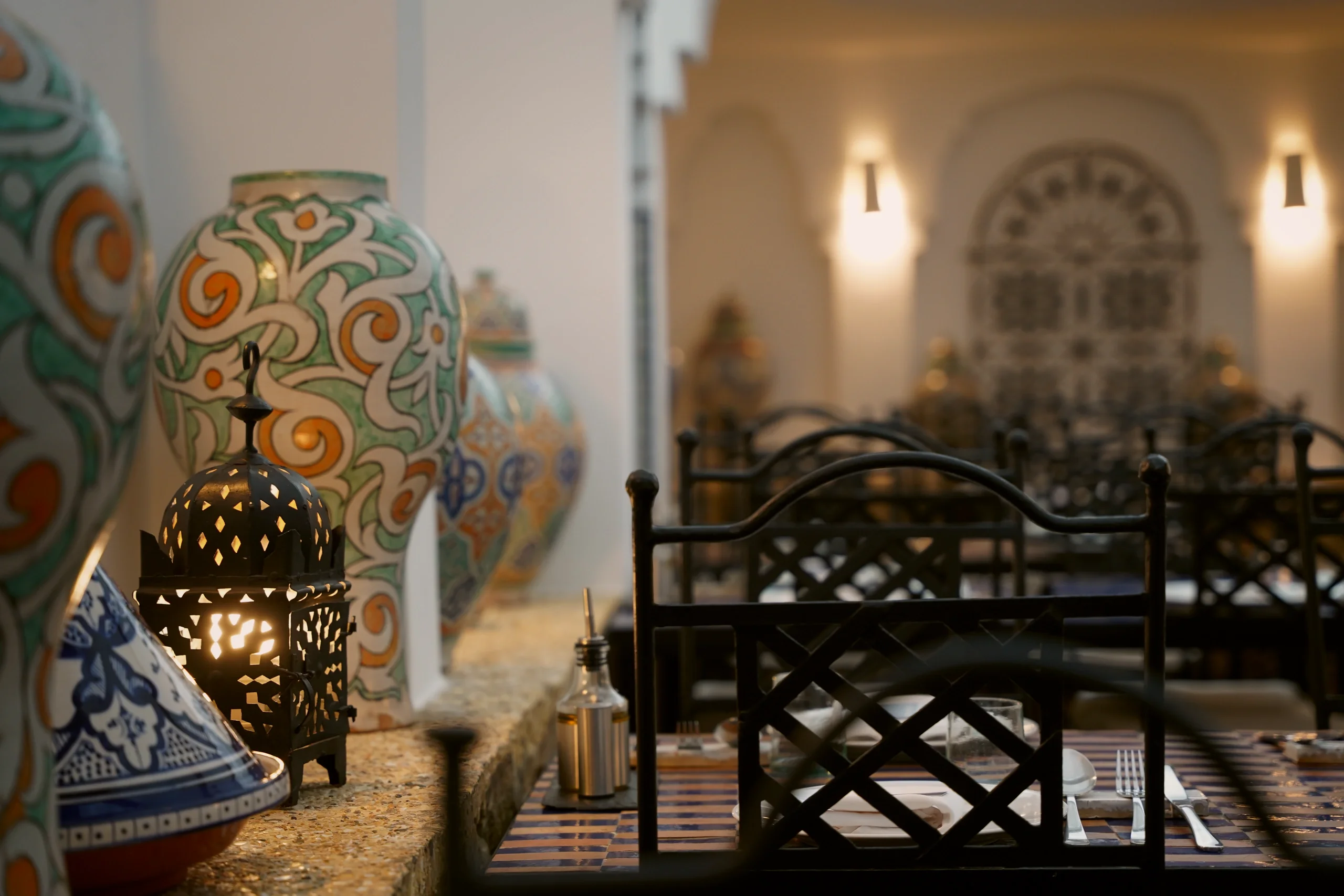 Moroccan vases and a lit lantern by the entrance, with the dining room tables in the background