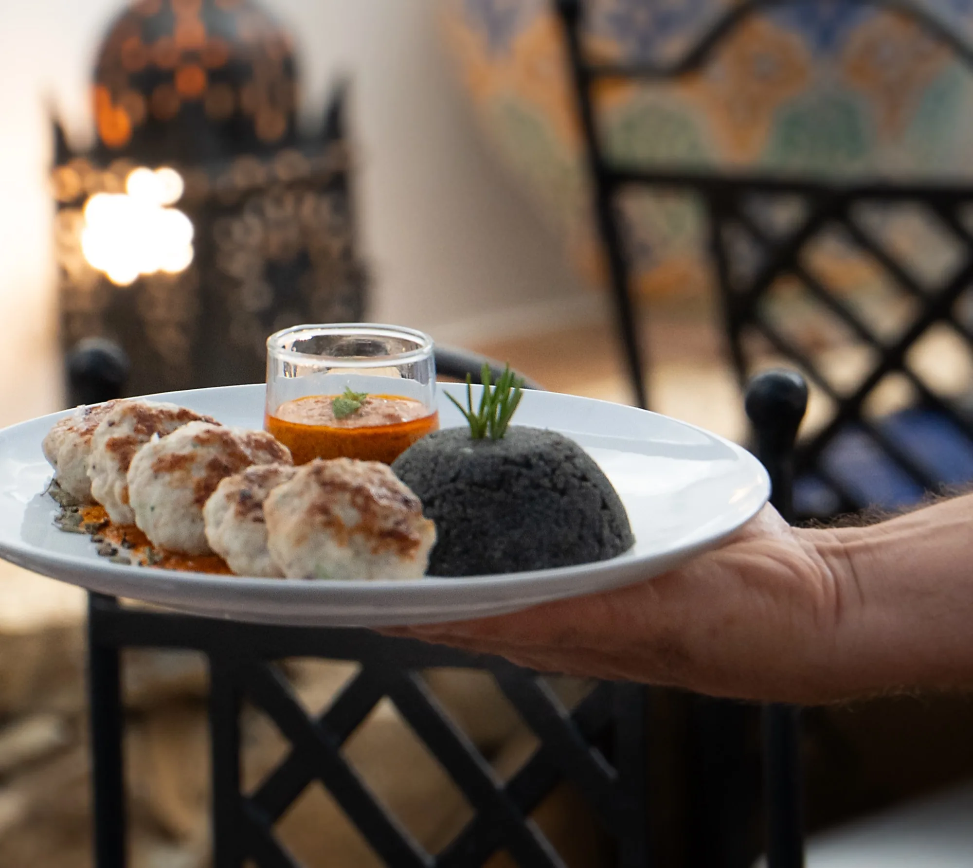 Keftas de sepia con salsa y couscous negro en un plato blanco