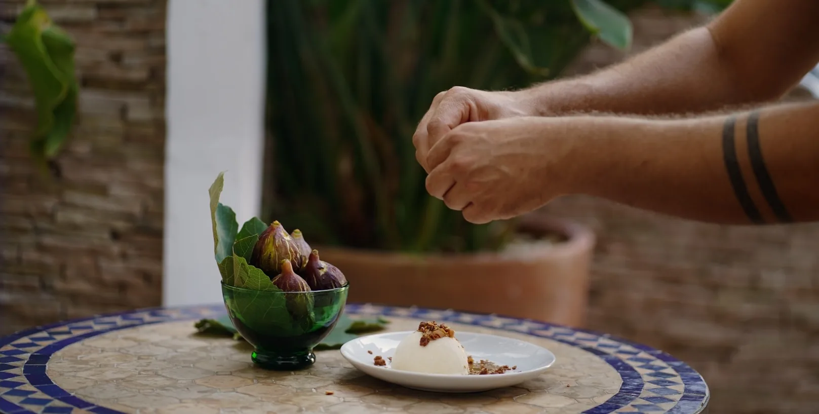 Cuenco de higos frescos junto a un postre emplatado en una mesa de azulejos
